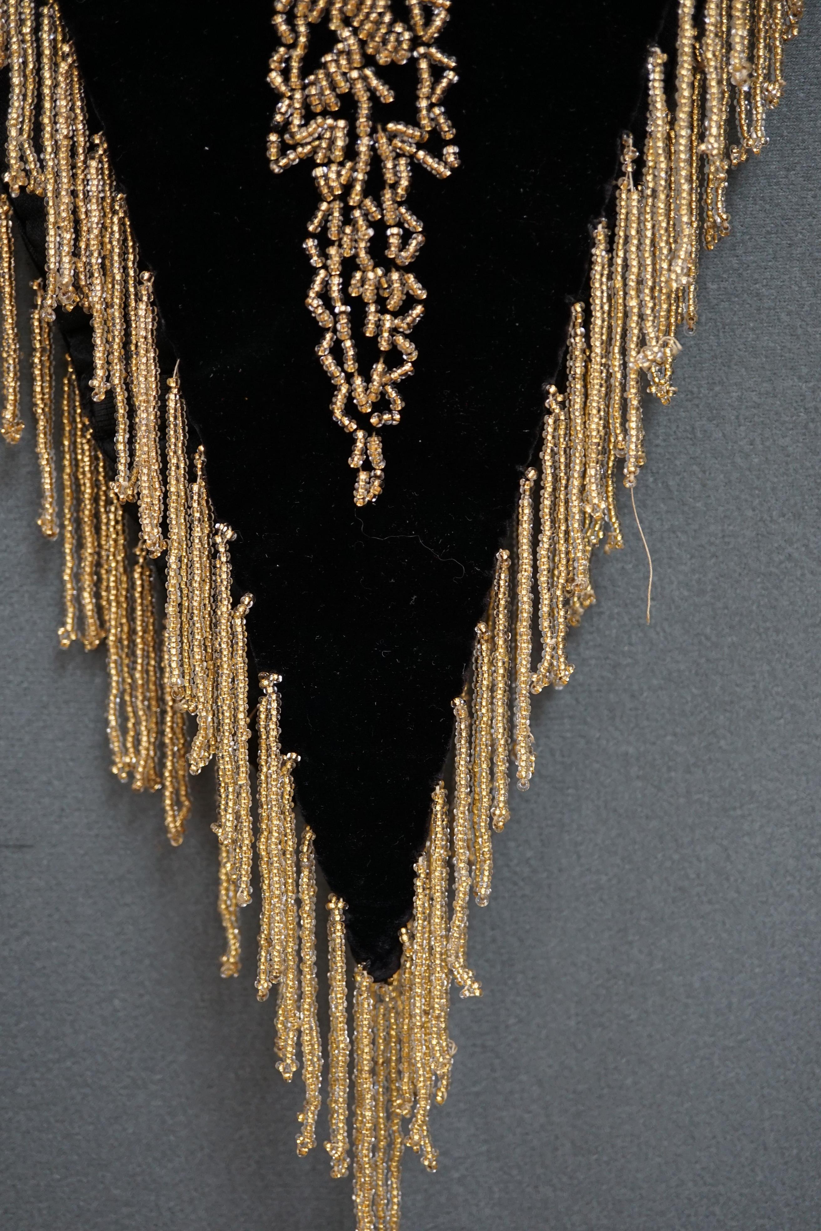 An Edwardian French black velvet and elaborately beaded evening over collar, with makers label, ‘Fillet’, designed with a high collar, front and back panels, all heavily bead worked in an intricate floral design, attache